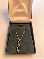 Full view of the necklace inside the open green velvet jewelry box with satin lining.