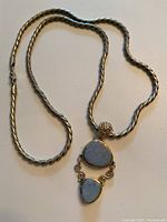 Full view of the thick silver chain with attached large two-tier opalescent pendant.