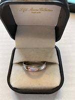 Mens titanium band ring inside a black H&H Showcase Collections presentation box with beige velvet lining.