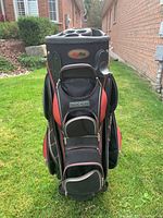 Front view showing multiple zippered compartments and top divided slots for clubs.