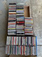 Top view of multiple stacks of CDs showing spines and covers with various titles and genres visible.