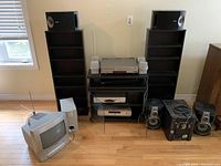 Wide shot showing entire entertainment system including TV, shelving cabinets, speakers, and other components