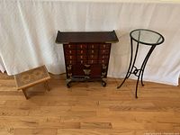 Full view showing all three items in the lot: wood footstool, wood chest/cabinet, and metal/glass side table