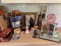 Overview of various home goods and decor including boxed bedding, porcelain figurines, wooden carvings, decorative boxes, and signs.