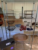 Front view of metal shelving unit filled with items such as storage containers, bowls, baskets, and paper towel holder.
