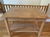 Front view showing the rectangular butcher block wooden top, drawer closed, and slatted shelf below.