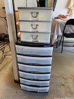 Front view of both plastic organizer drawer units stacked, showing black 6-drawer at bottom and grey 3-drawer on top