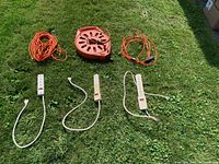 All items laid out on grass showing three orange extension cords and three white power bars