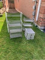Overall shot showing the three wire organizers and the plastic drawer unit all sitting on grass outside a brick house.