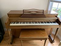 Front view of WINTER upright piano with matching bench in room.