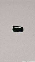 Close-up photo showing the emerald cut green tourmaline gemstone with rectangular shape and step facets.