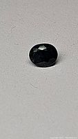 Photo showing oval cut blue sapphire from above with visible facets and dark medium blue color.