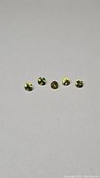 Five round diamond cut yellow sapphire gemstones shown in close-up, highlighting color and cut quality.