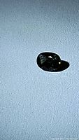 Photo showing the multicolored oval cut sapphire gemstone on a light textured surface with illumination emphasizing its color and shape.