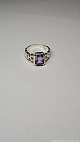 Front view of the sterling silver ring with a rectangular purple amethyst stone, showing the linked design of the band.