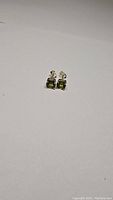 Pair of square cushion-cut apple green peridot stud earrings in 925 sterling silver with butterfly backs shown on white background.