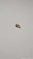 Close-up image of pear cut yellow peach colored natural sapphire gemstone on white background, showing its shape and color.
