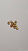 Parcel of bright golden yellow round cut sapphires scattered on a neutral background showing their size and color.