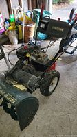 Front and top angled view of the Craftsman snow blower showing the engine, chute and tires.