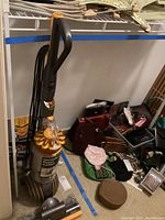 Dyson vacuum upright with handle and cord coiled showing the vacuum in standing position with surrounding items in background.