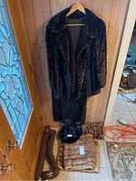 Overview of mink coat on hanger with stole, hat and pillow arranged below