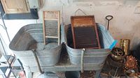 Full view of galvanized double wash tub connected side-by-side with wooden-framed washboards inside, placed against garage wall.