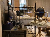 Overall view of bed area showing two small blue globes on box, floating globe parts, small table and large globe on adjacent table
