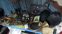 Wide shot of table with metal and plastic horses, brass horns, hats, and decorative metal pieces showing the lot contents clearly for condition and variety assessment.