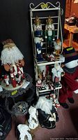 Full view of various Christmas decorations on shelves including wooden Nutcracker soldiers with gold crowns, cloth Santa with white beard, and other assorted santas and snowmen