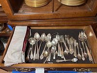 Full drawer view with assorted sterling utensils and cloth cases
