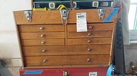 Front view of wood machinist chest showing 8 drawers with metal knobs and two metal latches on the top front.