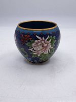 Full view of the round enameled pot showing cobalt blue background, floral design, and gold trimmed rim.