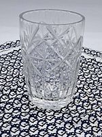 Clear crystal vase showing detailed cut geometric and star patterns on a black and white patterned cloth background.