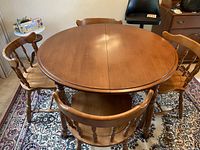 Full view of round table set up with four chairs around on patterned rug.