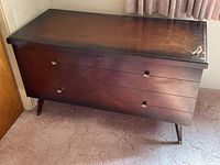 Front angle showing the full chest setup with three drawers and brass handles, dark wood finish.