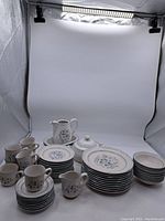 Overall view of the large set of Country Ware "Ashberry" stoneware including plates, cups, bowls, cream pitcher, sugar bowl, and serving dishes arranged on white background showing pattern and quantity.