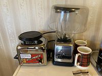 Vita-Mixer Maxi-4000 alongside Hamilton Beach blender and two plaid mugs on countertop