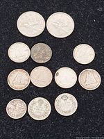 Top view of 12 Canadian silver coins arranged on a black surface, showing various national designs including Bluenose schooner and caribou.