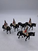 Front view of all four lead soldier figurines mounted on black horses, arranged in a loose group.