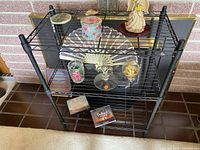 Full view of the metal adjustable rack with various decorative items placed on shelves, showing overall design and structure.