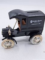 Side view showing black old car shape with Northern Electric Company Limited text and coin slot on roof.