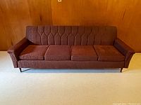 Front view of vintage couch showing tufted back and four seat cushions