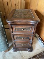 Front and top view of vintage solid wood side table showing three drawers and brass knobs, curved edges on top and base.