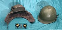 Photo showing the helmet, liner earflap cap, and patches arranged side by side on blue background