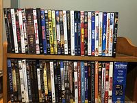 Front and spines of DVDs on a wooden rack showing titles and variety in movie genres.
