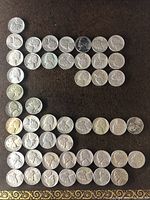 44 Jefferson nickels arranged on a dark surface, showing the obverse side with Thomas Jefferson profile, varying wear and patina, some coins possibly wartime issues with silver content.
