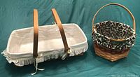 Two Longaberger baskets. Rectangular basket with plastic liner and lace trim liner fabric on left. Round Christmas-themed basket with fabric liner and wood handle on right.