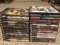 Stack of PlayStation 2 game cases showing titles including Harry Potter, All-Star Baseball 2002, Ghost Recon 2, ATV Offroad Fury 2, Medal of Honor Rising Sun, Metal Gear Solid, Spider-Man, Ford vs Chevy, Medal of Honor Frontline, Triple Play 2002, World Destruction League Thunder Tanks, Top Gun, ESPN 2K5.
