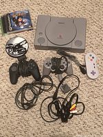 Sony PlayStation console with controllers, AV cables, and two games including Harry Potter.