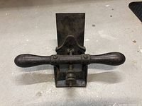 Front view of the Stanley No. 12 scraper showing wooden handles and metal base with blade angled upward.
